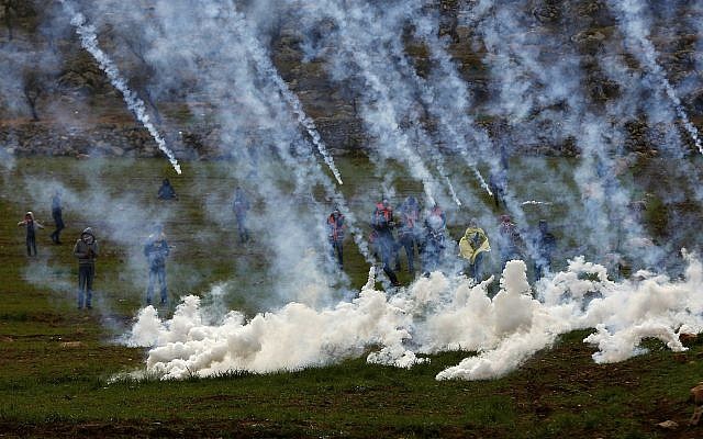 Tear gas canisters are fired by Israeli troops at Palestinians during clashes with Palestinians after the funeral of Hamdi Na'asan in the village of Mughayyir near the West Bank city of Ramallah, January 27, 2018 (AP Photo/Majdi Mohammed)