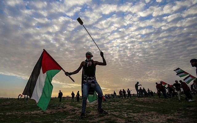 Illustrative: A Palestinian protester carries a national flag and a slingshot during a demonstration near the fence along the border with Israel, east of Gaza City, on February 1, 2019. (Said Khatib/AFP)