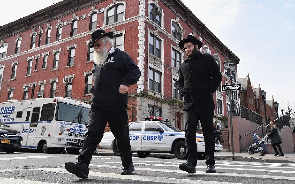 Jewish men walk past a 'Crown Heights Shmira Patrol' security vehicles in the Brooklyn neighborhood of Crown Heights on February 27, 2019 in New York. (Angela Weiss/AFP)