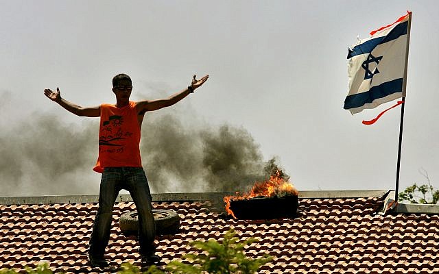 A settler gestures from a rooftop at Israeli troops approaching the Jewish settlement of Netzer Hazani, in the Gush Katif bloc of settlements, in the southern Gaza Strip, Aug. 18, 2005, during Israel's disengagement from Gaza. (AP Photo/Emilio Morenatti)