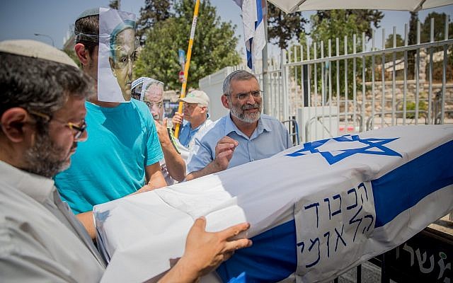 Otzma Yehudit candidates Itamar Ben Gvir, left, and Michael Ben-Ari, right, carry a mock coffin with a man wearing a Benjamin Netanyahu face mask during a protest in Jerusalem on July 27, 2017. (Yonatan Sindel/Flash90)