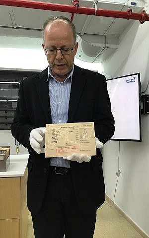 Dr. Haim Gertner holding an archived document from the Holocaust. (Courtesy)