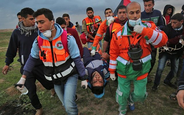 Illustrative: Palestinian paramedics carry away on a stretcher a youth injured during clashes following a demonstration along the border with Israel east of Gaza City on March 1, 2019. (SAID KHATIB / AFP)