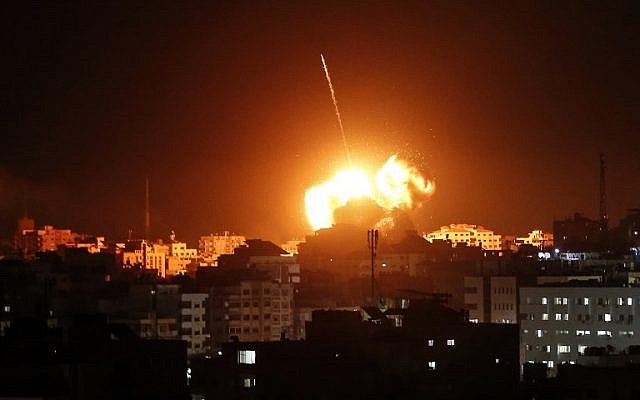 Una bola de fuego ilumina el cielo sobre un edificio que se cree alberga las oficinas de Ismail Haniyeh, el líder del grupo terrorista Hamas, durante los ataques israelíes en la ciudad de Gaza, el 25 de marzo de 2019. (Mahmud Hams / AFP)