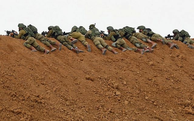In this file photo taken on March 30, 2018 Israeli soldiers keep position as they lie prone over an earth barrier along the border with the Gaza Strip in the southern Israeli kibbutz of Nahal Oz as Palestinians demonstrate on the other side commemorating Land Day. (Jack Guez/AFP)