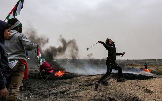 Illustrative: A Palestinian protester uses a slingshot to hurl a rock toward Israeli forces during clashes following a demonstration along the border with Israel in Malaka east of Gaza City on March 30, 2019. (Mahmud Hams/AFP)
