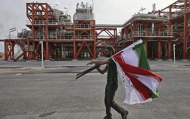 In this photo from March 16, 2019, an Iranian worker carries Iranian flags prior to an inauguration ceremony of a natural gas refinery at the South Pars gas field on the northern coast of the Persian Gulf, in Asaluyeh, Iran. (AP/Vahid Salemi)