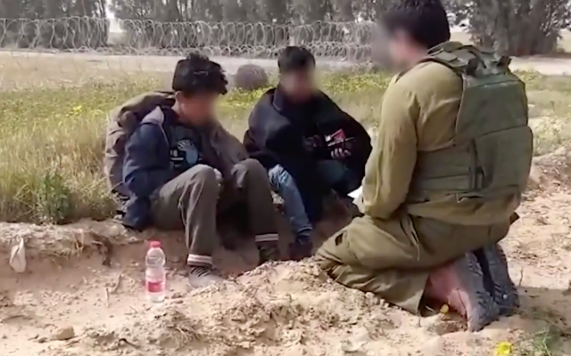 An IDF soldier sits with a pair of Palestinians who crossed into Israel from Gaza with a knife on March 30, 2019. (Screen capture/Twitter)
