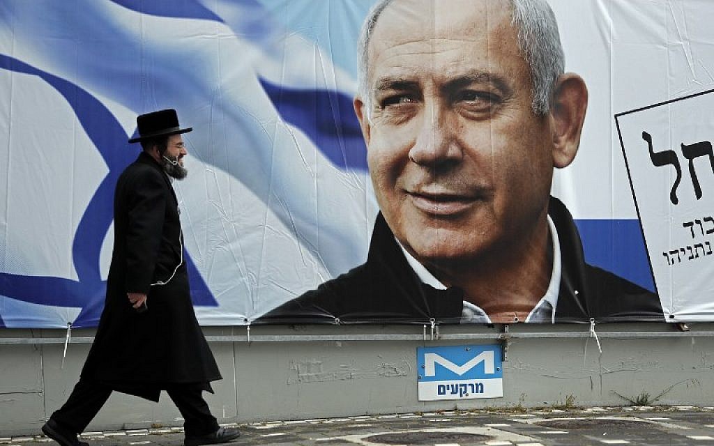 An ultra-Orthodox Jewish man walks past an electoral billboard bearing a portrait of Prime Minister Benjamin Netanyahu, in Jerusalem, on April 1, 2019. (Thomas Coex/AFP)