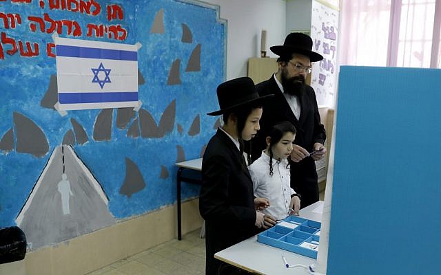 Children watch as an ultra-Orthodox Jewish man prepares to cast his vote during Israel's parliamentary elections on April 9, 2019 in Jerusalem. (Menahem Kahana/AFP)
