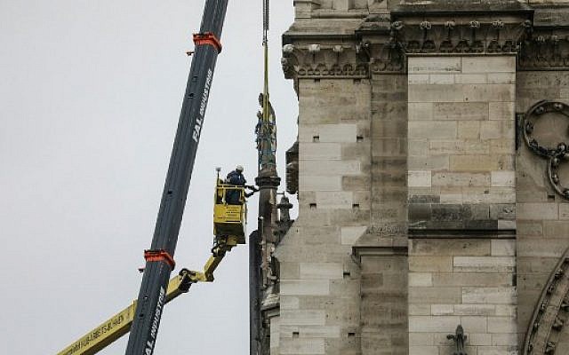 Workers remove a statue with a crane from Notre-Dame Cathedral in Paris on April 16, 2019, in the aftermath of a fire that devastated the cathedral. (Photo by LUDOVIC MARIN / AFP)