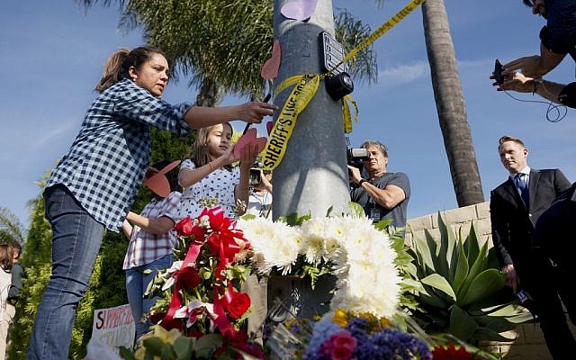 A woman and a young girl place notes on a light post near flowers across the street from the Chabad of Poway Synagogue after a shooting on April 27, 2019 in Poway, California. (SANDY HUFFAKER / AFP)