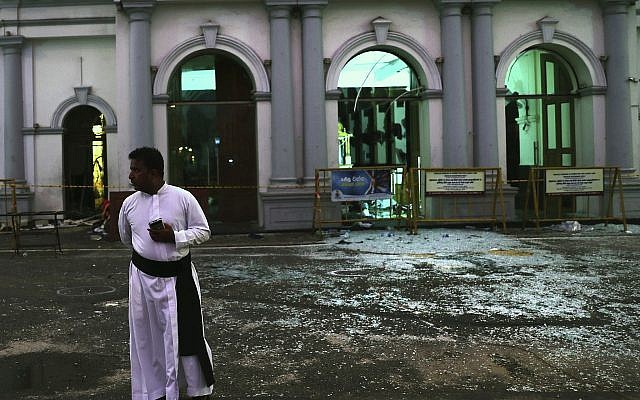 A Sri Lankan catholic priest stands near broken glass in front St. Anthony's Church in Colombo, Sri Lanka, Friday, April 26, 2019. Priests have allowed journalists inside St. Anthony's Church in Sri Lanka for the first time since it was targeted in a series of Islamic State-claimed suicide bombings that killed over 250 people.  (AP Photo/Manish Swarup)