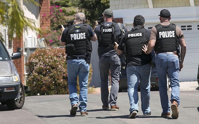 Heavily armed San Diego police officers approach a house thought to be the home of 19-year-old John T. Earnest, the alleged shooter in the fatal attack at a synagogue in Poway on April 27, 2019, in San Diego, California. (John Gibbins/ The San Diego Union-Tribune via AP)