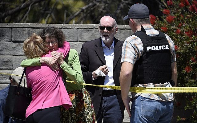 Two people hug as another talks to a San Diego County Sheriff’s deputy outside of the Chabad of Poway Synagogue Saturday, April 27, 2019, in Poway, Calif. (AP/Denis Poroy)