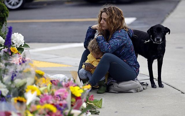 A woman and a child pause at a growing memorial across the street from the Chabad of Poway synagogue in Poway, California, following a deadly shooting there. April 29, 2019 (AP Photo/Greg Bull)