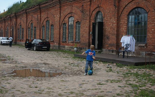 A boy playing soccer at the entrance to the former concentration camp known as the Seventh Fort in Kaunas, Lithuania, on July 12, 2016. (JTA/Cnaan Liphshiz)