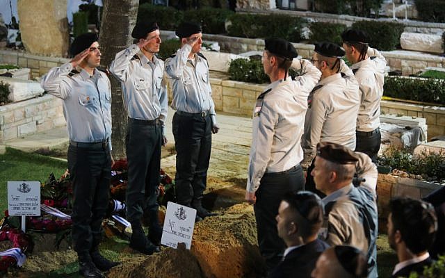 Israeli soldiers salute by the fresh grave of Zachary Baumel, who went missing at the Battle of Sultan Yacoub in 1982, during his funeral at the Mount Herzl Military cemetery in Jerusalem on April 4, 2019. (Hadas Parush/Flash90)