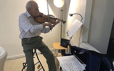 Nonagenarian Eric Sargon, who played for The Beatles, Eric Clapton and the BBC Orchestra, plays his viola in his new Jerusalem apartment (Jessica Steinberg/Times of Israel)