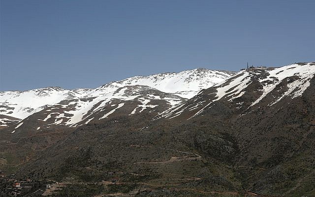 An Israeli military position, right, is seen on the top of Mount Hermon in the Golan Heights, where the borders between Israel, Syria and Lebanon meet. April 9, 2019. (AP Photo/Hussein Malla)