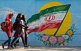 Young girls walk in front of a mural showing the Iranian national flag in the center of the capital Tehran, April 23, 2019. (Atta Kenare/AFP)