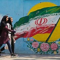 Young girls walk in front of a mural showing the Iranian national flag in the center of the capital Tehran, April 23, 2019. (Atta Kenare/AFP)