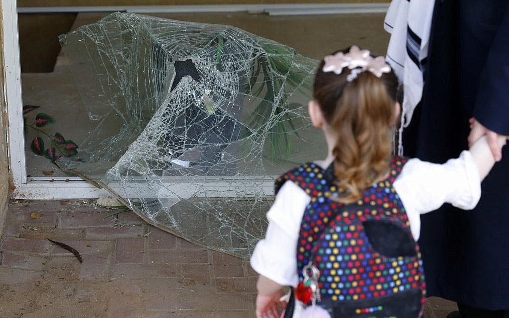 An Israeli child on May 6, 2019, looks at shattered glass at the entrance to a building damaged by a rocket strike from the Gaza Strip, in the southern Israeli city of Ashdod. (Jack Guez/AFP)