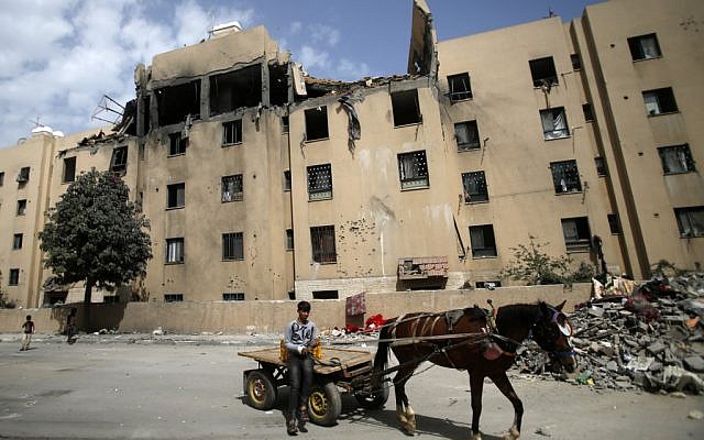 A young Palestinian rides a horse-drawn cart on May 6, 2019, in front of a building that was damaged during an Israeli airstike on Beit Lahia in the northern Gaza Strip. (MOHAMMED ABED / AFP)