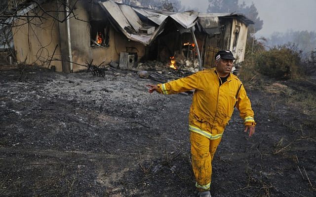 A firefighter walks past a burning house amid extreme heat wave in Kibbutz Harel in central Israel on May 23, 2019. (Ahmad Gharabli/AFP)