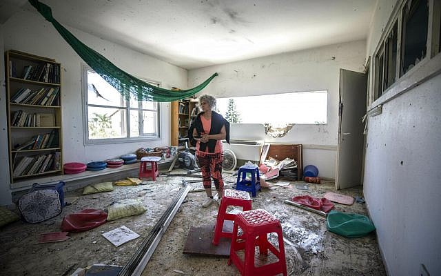 A woman looks at the damage caused by a rocket fired from Gaza that hit a house in a community in Israel near the border with Gaza, Saturday, May 4, 2019. (AP Photo/Tsafrir Abayov)