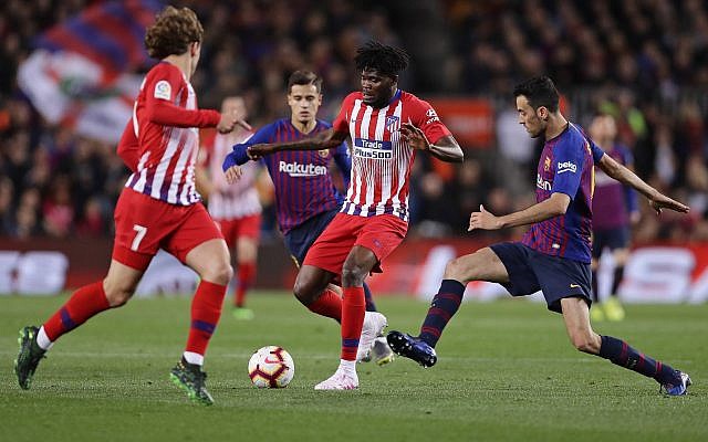 Atletico forward Antoine Griezmann, left, Atletico midfielder Thomas Partey, and Barcelona's Sergio Busquets, right, vie for the ball during a Spanish La Liga soccer match between FC Barcelona and Atletico Madrid at the Camp Nou stadium in Barcelona, Spain, Saturday April 6, 2019. (AP Photo/Manu Fernandez)