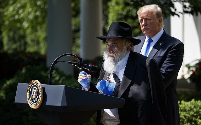 US President Donald Trump looks on as Rabbi Yisroel Goldstein, survivor of the Poway, California synagogue shooting, speaks during a National Day of Prayer event in the Rose Garden of the White House, May 2, 2019. (AP/Evan Vucci)