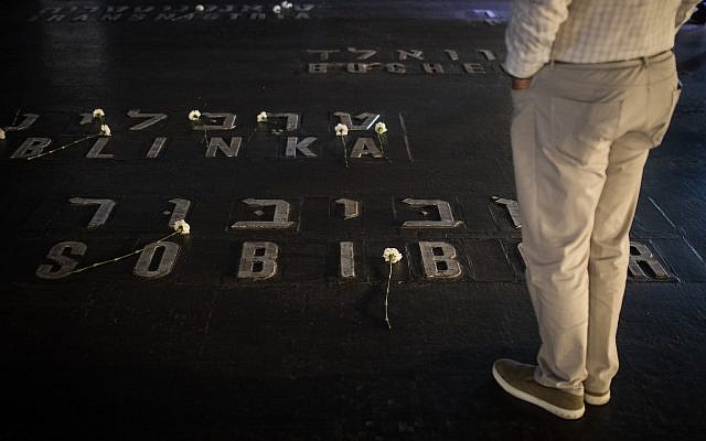 Relatives and friends of Holocaust survivors place flowers on names of concentration camps seen on the floor of the Hall of Remembrance at Yad Vashem on Holocaust Remembrance Day April 12, 2018. (Hadas Parush/Flash90)