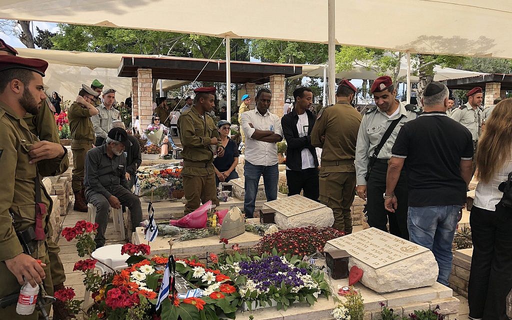 Bereaved family members stand in front of their loved one’s grave at Ashkelon’s military cemetery on Memorial Day, May 8, 2019. (Jacob Magid/Times of Israel)