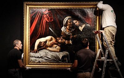 Workers hang on a wall a painting believed by some experts to be Caravaggio's 'Judith Beheading Holofernes' for its public presentation at the Drouot auction house in Paris on June 14, 2019 before it goes under the hammer on June 27 in Toulouse, the city where it was discovered five years ago. (Francois Guillot/AFP)