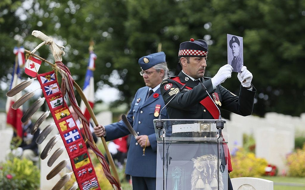 A member of the Canadian Armed Forces holds a photo of a Canadian World War II soldier during a ceremony at the Beny-sur-Mer Canadian War Cemetery in Reviers, Normandy, France, June 5, 2019. The ceremony was held for Canadians who fell on the beaches and in the bitter bridgehead battles of Normandy during World War II. (AP Photo/David Vincent)