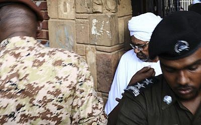 Sudan's ousted president Omar al-Bashir is escorted into a vehicle as he returns to prison following his appearance before prosecutors over charges of corruption and illegal possession of foreign currency, in Khartoum the capital of Sudan on Sunday June 16, 2019. (AP Photo/Mahmoud Hjaj)