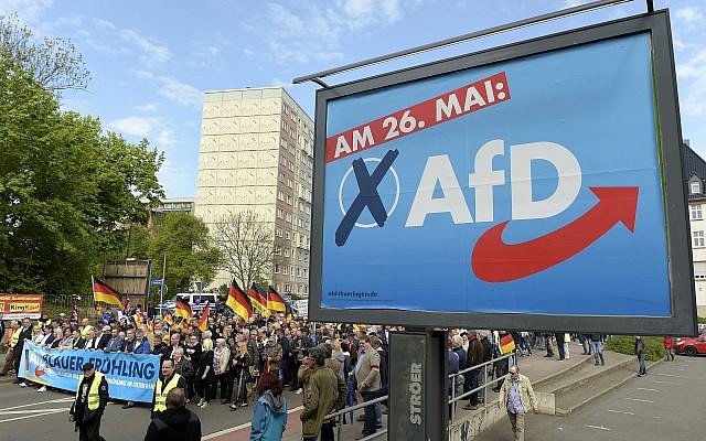 AfD supports walks along a party elections poster in Erfurt, Germany, Wednesday, May 1, 2019. The far-right Alternative for Germany launches its European parliament election campaign in the eastern city of Erfurt.(AP Photo/Jens Meyer)