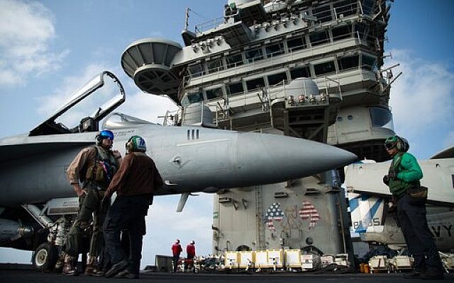 A pilot speaks to a crew member by an F/A-18 fighter jet on the deck of the USS Abraham Lincoln aircraft carrier in the Arabian Sea on June 3, 2019. (AP Photo/Jon Gambrell)