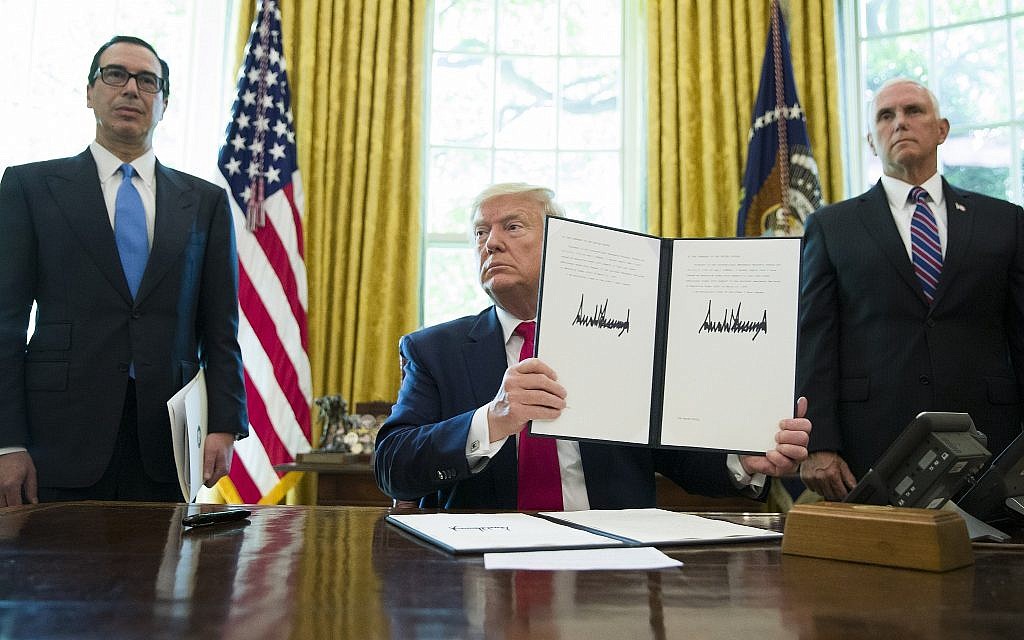 Then-US president Donald Trump holds up a signed executive order to increase sanctions on Iran, in the Oval Office of the White House, June 24, 2019, in Washington. Trump is accompanied by then-treasury secretary Steve Mnuchin, left, and then-vice president Mike Pence. (AP Photo/Alex Brandon)