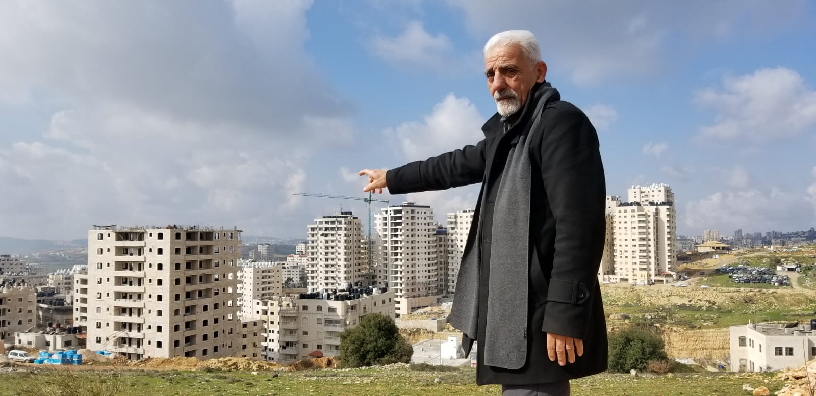 Munir Zughayer, an activist who leads a committee that frequently complains to the Jerusalem Municipality about the state of services in Kafr Aqab, points to a number of buildings that were built in contravention of regulations on February 20, 2019. (Adam Rasgon/Times of Israel)