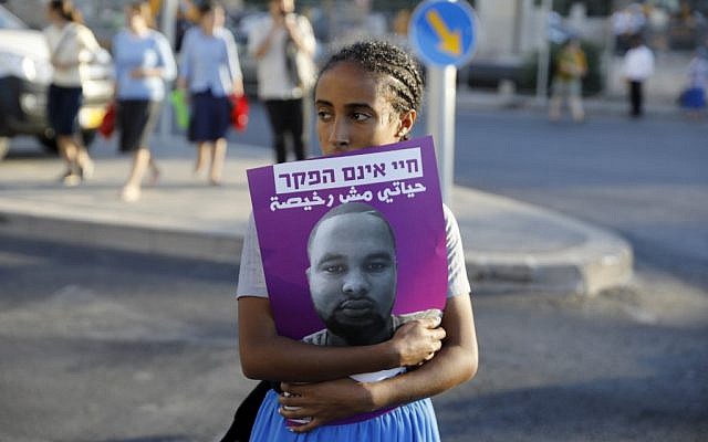 An Israeli woman holds a poster of Solomon Tekah, a young man of Ethiopian origin who was killed by an off-duty police officer, as members of the Israeli Ethiopian community block the main entrance to Jerusalem on July 2, 2019 to protest his killing. (MENAHEM KAHANA / AFP)