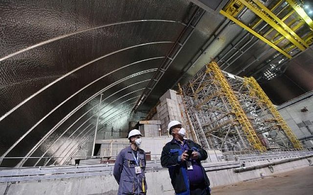 Employees stand inside the New Safe Confinement (NSC) new metal dome designed and built by French consortium Novarka encasing the destroyed reactor at Chernobyl plant on July 10, 2019, in Chernobyl. (Sergei Supinsky/AFP)