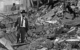 In this photo from July 18, 1994, a man walks over the rubble left after of the Argentinian Israeli Mutual Association (AMIA) building in Buenos Aires after it was targeted in a deadly bombing. (Ali Burafi/AFP)