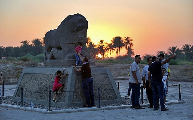 People stand near the Lion of Babylon at the archaeological site of Babylon, Iraq, Friday, July 5, 2019.(AP Photo/Anmar Khalil)