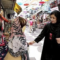 In this July 3, 2019 photo, a woman inspects a headscarf at a market in downtown Tehran, Iran (AP Photo/Ebrahim Noroozi)