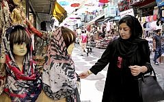 In this July 3, 2019 photo, a woman inspects a headscarf at a market in downtown Tehran, Iran (AP Photo/Ebrahim Noroozi)