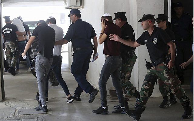 Israeli suspects cover their faces with their shirts as they arrive at the Famagusta courthouse in Paralamni, Cyprus, July 26, 2019 (AP Photo/Petros Karadjias)