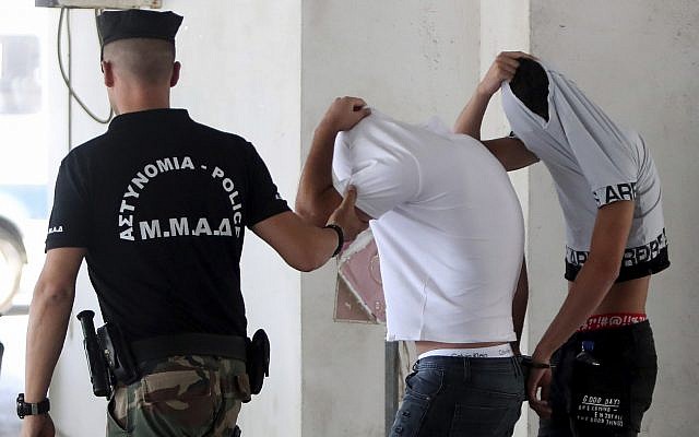 Israeli suspects cover their faces with their shirts as they arrive at the Famagusta courthouse in Paralamni, Cyprus, July 26, 2019 (AP Photo/Petros Karadjias)