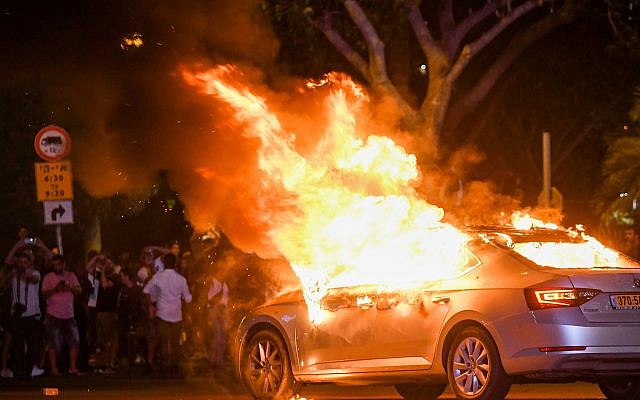A car is seen on fire during a protest following the death of 19-year-old Ethiopian, Solomon Tekah who was shot and killed few days ago in Kiryat Haim by an off-duty police officer, in Tel Aviv, July 2, 2019. (Flash90)